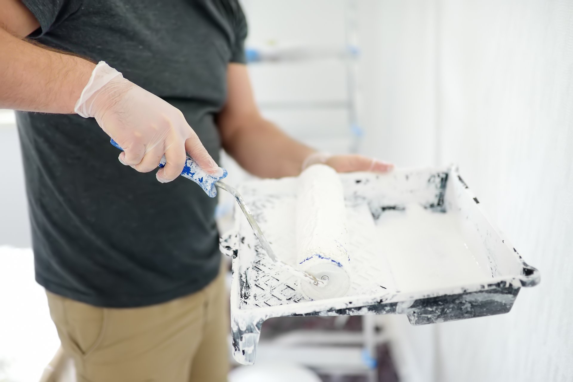 Painter loading a roller with white wall paint